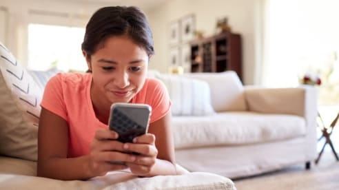 Young girl using her mobile phone using access to the internet made possible by the Donate your Data program.