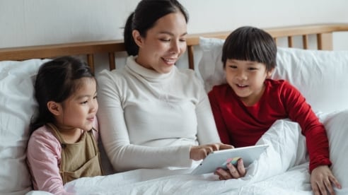Family in bed all looking at a tablet