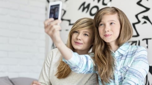 Girls looking at phone taking a selfie Girls looking at phone taking a selfie