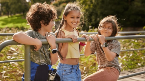 three kids playing outside wearing smartwatches