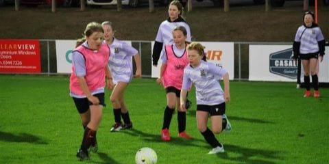 three young girls from the Launceston City Football Club playing football