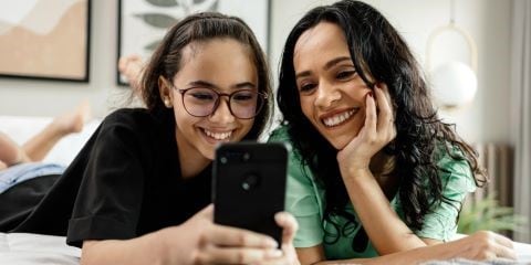 Mother and daughter smiling at a phone