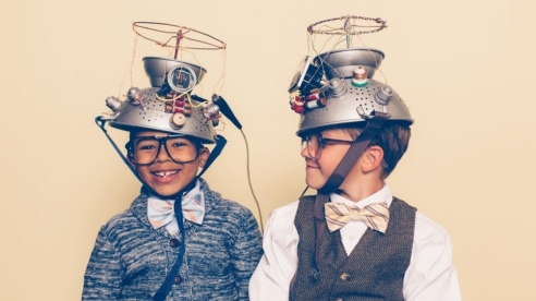 two young boys looking professorial, wearing bow ties, vests and home-made mind reading helmets made from colanders.